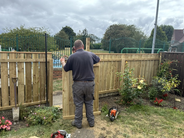 Fitting a fence panel with the tools laid out on the lawn