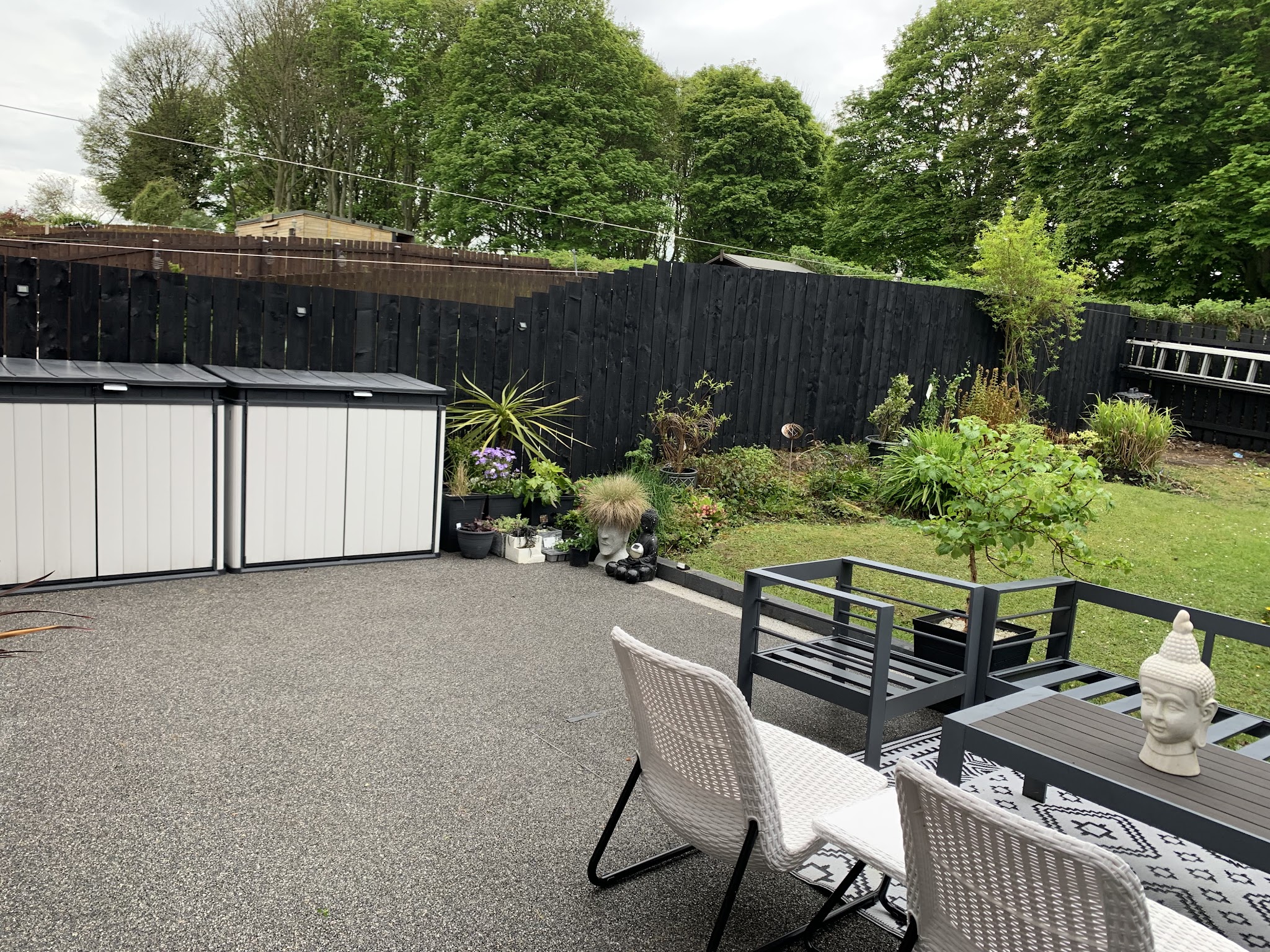 A finished garden with a black-stained fence, resin patio and planted borders