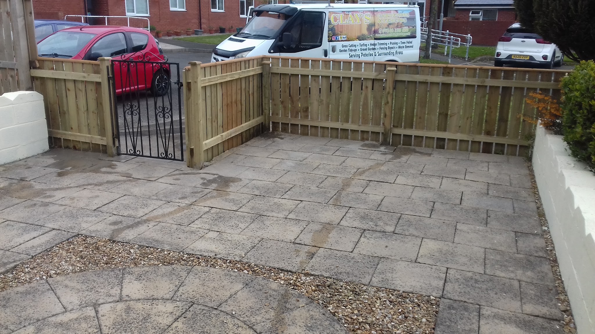 A new picket-style timber fence with a black gate on a paved patio
